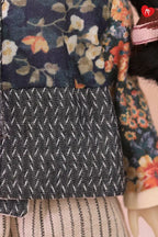 Close-up detail of a doll outfit featuring a navy floral jacket with a dark gray patterned cuff and a striped beige skirt.