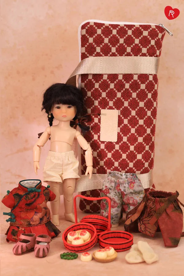 A doll with black hair stands beside a large red-and-white patterned storage bag, surrounded by doll accessories including a red outfit, shoes, basket, and small food pieces on a pink background.